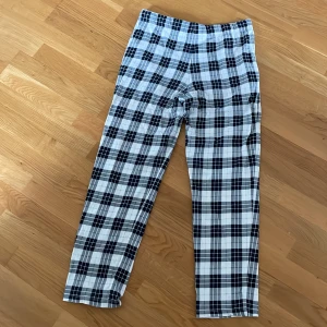 Rutig byxa från Kappahl - Snygga rutiga byxor från Kappahl i svart och vitt. Byxorna har en bekväm passform med snörning i midjan för justerbarhet. Perfekta för en avslappnad stil.