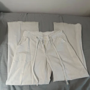 Vita linnebyxor med dragkedja - Snygga vita linnebyxor med dragkedja och knapp framtill. Byxorna har en avslappnad passform och praktiska fickor både fram och bak. Perfekta för en stilren och bekväm look.