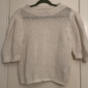 Vit stickad tröja - Säljer en mysig vit stickad tröja med trekvartsärm. Perfekt för kyliga dagar med sin luftiga och bekväma design. Tröjan har en rund hals och ribbade kanter som ger en stilren look. Passar bra till både jeans och kjol.