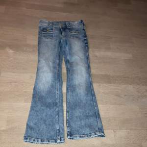 Säljer ett par snygga blå bootcut jeans från H&M i bra skick. De har låg midja och justerbar midja för perfekt passform. Jeansen har två knappar fram och coola fickdetaljer. Perfekta för en avslappnad stil! Endast Andvända 2 gånger💗