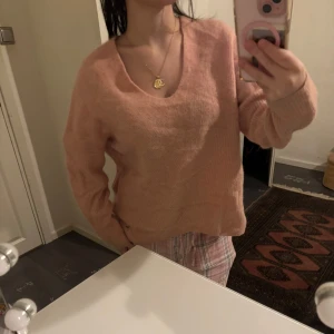 Rosa stickad tröja - Mysig rosa stickad tröja i bra skick. Perfekt för kyliga dagar med sin mjuka och bekväma passform. Tröjan har en v-ringad hals och långa ärmar, vilket gör den idealisk för både vardag och mysiga hemmakvällar. Passar perfekt till jeans eller leggings! alpacka ull blend