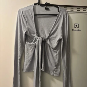 Ljusblå långärmad topp från Gina Tricot - Säljer en superfin ljusblå topp från Gina Tricot i storlek M. Den har långa ärmar och en snygg knytning framtill som ger en cool look. Perfekt för både vardag och fest!