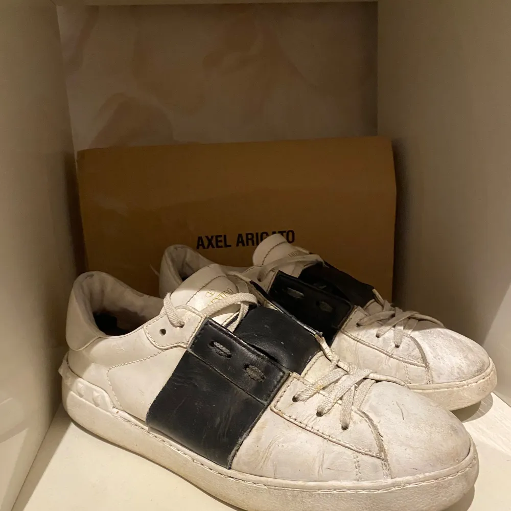 Säljer ett par vita sneakers från Valentino Garavni i bra skick. De har en cool svart detalj på sidan och klassisk snörning. Perfekta för både vardag och fest! Skorna är lite smutsiga men kan enkelt rengöras för att se fräscha ut igen. Skorna är äkta bara till att fråga har fått äkthetsbevis av många företag men ställ era frågor Mvh! . Skor.