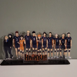 Haikyuu!! akrylställ med karaktärer - Säljer ett coolt akrylställ med karaktärerna från Haikyuu!! Alla spelarna står i sina volleybolluniformer med nummer och det finns en logga längst ner. Perfekt för fans av serien att ha som dekoration på hyllan eller skrivbordet!