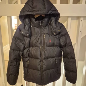 Svart pufferjacka  Polo Ralph Lauren vinterjacka junior str XL (18-20år) - Säljer en snygg svart pufferjacka från Polo Ralph Lauren i storlek junior XL (18-20år).  Jättefint skick