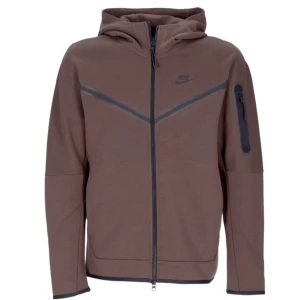 Brun Nike Tech Hoodie - Säljer en snygg brun hoodie från Nike i mycket bra skick. Den har en dragkedja framtill och en praktisk ficka med dragkedja på ärmen. Perfekt för höst och vår, med en normal passform och långa ärmar. Grym för både chill och aktivitet!