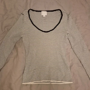 Randig långärmad tröja från H&M - Säljer en snygg randig tröja från H&M i storlek M. Den är vit med svarta ränder och har en v-ringad hals. Tröjan är långärmad och perfekt för både vår och höst. Ärmarna är lite flared, vilket är sjukt snyggt. Den är i bra skick och passar till många olika outfits! 
