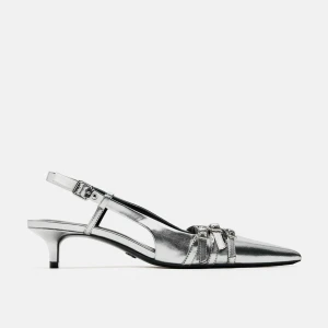 Silvriga slingback-pumps med klack - Snygga silvriga slingback-pumps med spetsig tå och låg klack. De har eleganta spänndetaljer och en justerbar rem runt hälen. Perfekta för en festlig kväll eller en stilfull dag på stan.