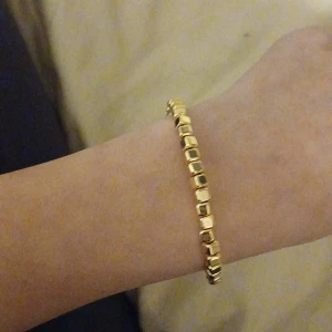 Guldarmband med fyrkantiga länkar - Snyggt och elegant guldarmband med fyrkantiga länkar. Perfekt för både vardag och fest. Armbandet har en klassisk design som passar till alla outfits. Det är i mycket bra skick och redo att bäras av sin nya ägare.