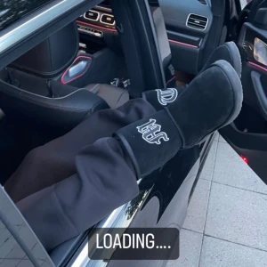 Tuttolente Uggs - Säljer ett par svarta boots med en cool logga på sidan. De ser riktigt bekväma ut och är perfekta för att chilla i bilen eller hemma. Passar bra till avslappnade outfits och håller fötterna varma.