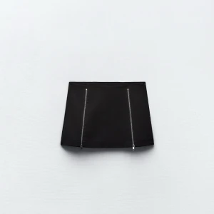 Svart kjol med dragkedjor - Snygg svart kortkjol med två dragkedjor framtill. Perfekt för en kväll ute eller en trendig vardagslook. Kjolen är i nytt skick och har en stilren design som passar till det mesta. 