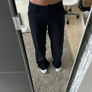 Svarta/mörkblåa kostymbyxor - Säljer ett par stilrena mörkblåa kostymbyxor i mycket bra skick. De är lågmidjade/midwaist och har en straight passform som ger en klassisk look. De är otroligt sköna och väldigt fina❤️