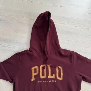 Vinröd hoodie Ralph Lauren - Säljer en  vinröd hoodie från Ralph Lauren med  Polo-logga i gult på bröstet. Hoodie har använts några enstaka gånger. Nypris: 1699 