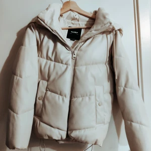 Vit pufferjacka från Pull & Bear  - Säljer en supermysig vit pufferjacka från Pull & Bear . Den har en dragkedja framtill och en stor luva för extra värme. Perfekt för kyliga dagar och har en stilren look som passar till allt. Jackan är i mycket bra skick och redo för nya äventyr!