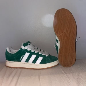 Gröna Adidas Campus sneakers - 🟢🟩 Adidas Campus sneakers i mocka med vita detaljer och snörning. En klassisk design med tre vita ränder på sidan och en gummisula. Perfekta för både vardag och fest!     Box ingår!📦