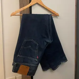 Säljer ett par klassiska Levi's 501 jeans i mörkblå denim. De har den ikoniska raka passformen och är i mycket bra skick, förutom några slitningar på botten som syns på bilderna😀 Perfekta för vardag och passar till allt🙌 Storleken är W30 L30. 