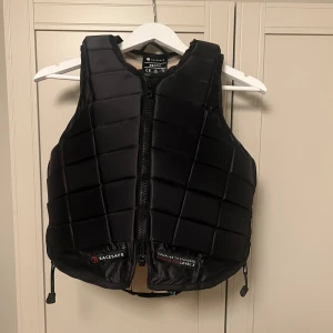 Ridväst/skyddsväst från Racesafe (helt oanvänd) - Säljer en svart skyddsväst från Racesafe i storlek  vuxen XS i LEVEL 3. Västen har en quiltad design med dragkedja framtill och är perfekt för ridning. Den är i helt nytt skick och ger bra skydd och komfort. Perfekt för säkerhet vid ridning! Pris kan diskuteras 