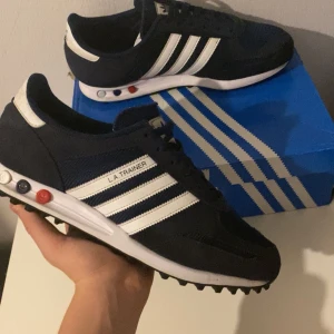Svarta Adidas LA Trainer sneakers - Säljer ett par överfeta LA Trainers i storlek 45. Skicket är 9/10 och den enda defekten ser du på bild tre, alltså inget man märker av. Box kommer med och har även kvitto. Har du några fler frågor eller vill se fler bilder släng iväg ett dm!