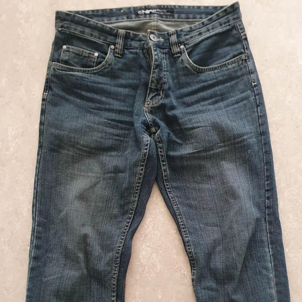 Säljer ett par klassiska blå jeans från Shine i storlek W33 L34. De har en normal passform och är tillverkade i slitstarkt denim. Perfekta för vardagsbruk med en tidlös stil. Dragkedja och knapp framtill.. Jeans & Byxor.