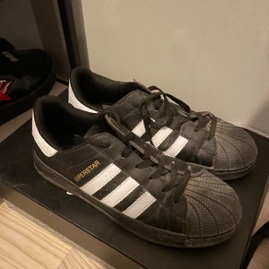 Svarta och vita Adidas Superstar - Säljer ett par Adidas Superstar i svart och vitt. Fick dom i present men har inte använt så mycket. De är i bra skick men lite dammiga framme men de går att ta bort. Passar både storlek 40 och 41. 