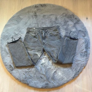 Grå Levi’s Premium jeans, Lot 551 - Säljer ett par grå Levis Premium jeans i bra skick. De har en snygg, sliten look med fransiga benslut och klassisk femficksdesign. Perfekta för en avslappnad stil. Passar både till vardags och fest!  Nästan oanvända! Ny pris runt 1250kr🤩