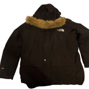North face parka jacka - Säljer en svart vinterjacka från The North Face i storlek XL. Jackan har en avtagbar huva med fuskpäls och är perfekt för kalla vinterdagar. Vid snabb affär kan priset diskuteras nypris-5000kr