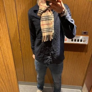 Rutig halsduk från Burberry - Säljer en halsduk från Burberry i 100% lammull. Perfekt nu till kall höst o vinter! Den är i mycket bra skick utan några skador. Passar både killar och tjejer. 
