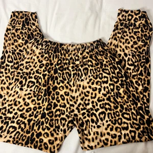 Leopardmönstrade byxor - Säljer ett par supercoola leopardmönstrade byxor. De är loose fit och har en elastisk midja för extra komfort. Perfekta för en avslappnad dag eller en utekväll när du vill sticka ut. Materialet känns mjukt och skönt mot huden. Passar perfekt för dig som älskar djurmönster och vill ha något unikt i garderoben! 🐆✨