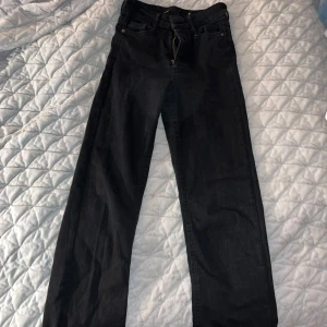 Svarta jeans - Säljer ett par svarta jeans i bra skick. De är bootcut och har en klassisk design med dragkedja och knapp.