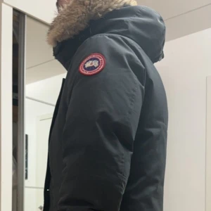 Svart vinterjacka från Canada Goose - Säljer en svart vinterjacka från Canada Goose i mycket bra skick. Jackan har en pälsfodrad huva och är perfekt för kalla vinterdagar. Den har långa ärmar och flera praktiska fickor. Perfekt för dig som vill hålla dig varm och stilren i vinter! Köpt på nk för 5 år sen den sista modellen med äkta päls chateu parka Obs! Zippen är trasig vid bröstfickan, sen är både ärmarna är lite sönder därav billigt pris, nypris 18000kr säljer den för 6500