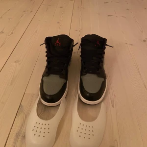 Nike Air Jordans i svart och grått - Säljer ett par Nike Air Jordans i svart och grått. Skorna är i mycket bra skick och har en klassisk design med snörning. Perfekta för både vardag och fest. Storlek 37.5 EU. Passa på att köpa dessa snygga sneakers!