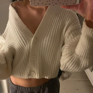 Vit ribbad kofta - Säljer en superfin vit ribbad kofta med stora knappar framtill. Den är croppad och har en mysig, oversized passform. Perfekt för höst och vår!