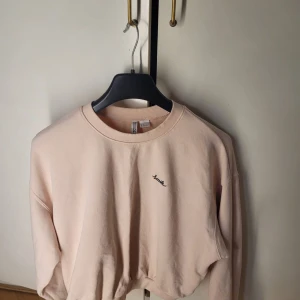 Beige sweatshirt med broderad text - Säljer en superfin beige sweatshirt i storlek XL. Den har en enkel och stilren design med ordet 'Smile' broderat på bröstet. Perfekt för en avslappnad look! Tröjan är i mycket bra skick och passar perfekt för höst och vår.