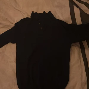 Mörkblå tröja med krage  - Snygg mörkblå tröja med ribbad krage och knappar framtill. Tröjan är från John Henric med lappen i tröjan har gått av . Passar storlek Xs