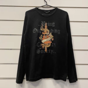 RG512 Långärmad Tröja y2k ed hardy - Långärmad Tröja ifrån RG512 i storlek Small. Påminner om Ed Hardys designstil och det färgade trycket är täckt med genomskinliga stenar som ger den en najs effekt.