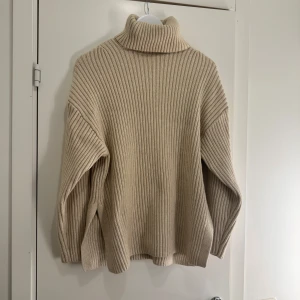 Stickad tröja - Stickad tröja med hög hals och slits på sidorna. Använd enstaka gånger och är i mycket bra skick utan skavanker. Storlek XS