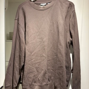 Brun sweatshirt från H&M Essentials - Säljer en brun sweatshirt från H&M Essentials. Tröjan har en klassisk rund hals och långa ärmar. Perfekt för en avslappnad stil.