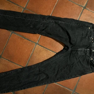 Svarta Levi's 501 jeans - Klassiska svarta Levi's 501 jeans i denim. De har en rak passform och knappgylf. Perfekta för en stilren look.