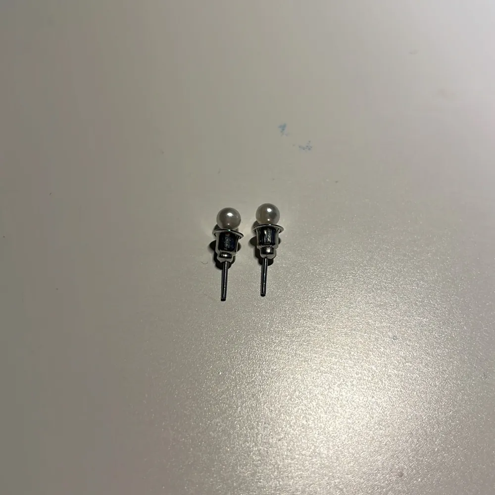 Eleganta små pärlörhängen med silverfäste. Perfekta för en stilren look.. Asusteet.