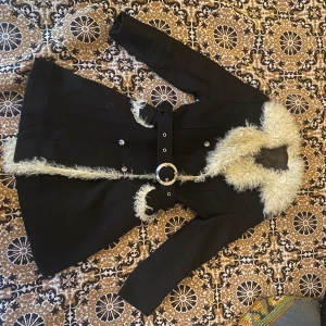 Svart kappa med pälsdetaljer - Svart kappa med pälsdetaljer, midjebältet går att juste. I nästan oanvänt skick!  