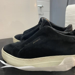 Svarta sneakers från Axel Arigato - Snygga svarta sneakers från Axel Arigato med vit sula. Tillverkade i mocka för en stilren look. Perfekta för en avslappnad men trendig stil. Ser lite använt ut. Storlek 37 men passar 37.5. Innersulan är 24,5cm!! 