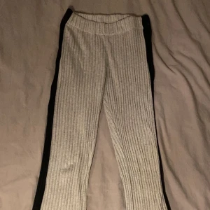 Grå ribbade byxor - Snygga grå ribbade byxor med en bekväm passform. Perfekta för en avslappnad stil med en touch av elegans. De har en lätt utsvängd design som ger en modern look.