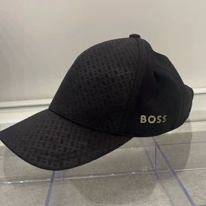 Svart keps från Boss - Säljer min keps nu för jag inte använder den längre. Den är i bra skick. Priset är pågrund av att den inte längre säljs