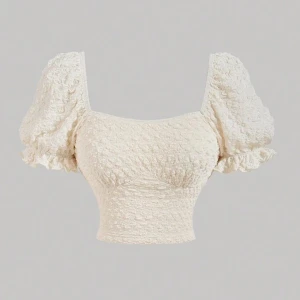 Vit puffärmad topp - Charmig vit topp med puffiga kortärmar och en texturerad yta. Den har en fyrkantig halsringning och är croppad, vilket ger en trendig look. Perfekt för sommarens varma dagar.