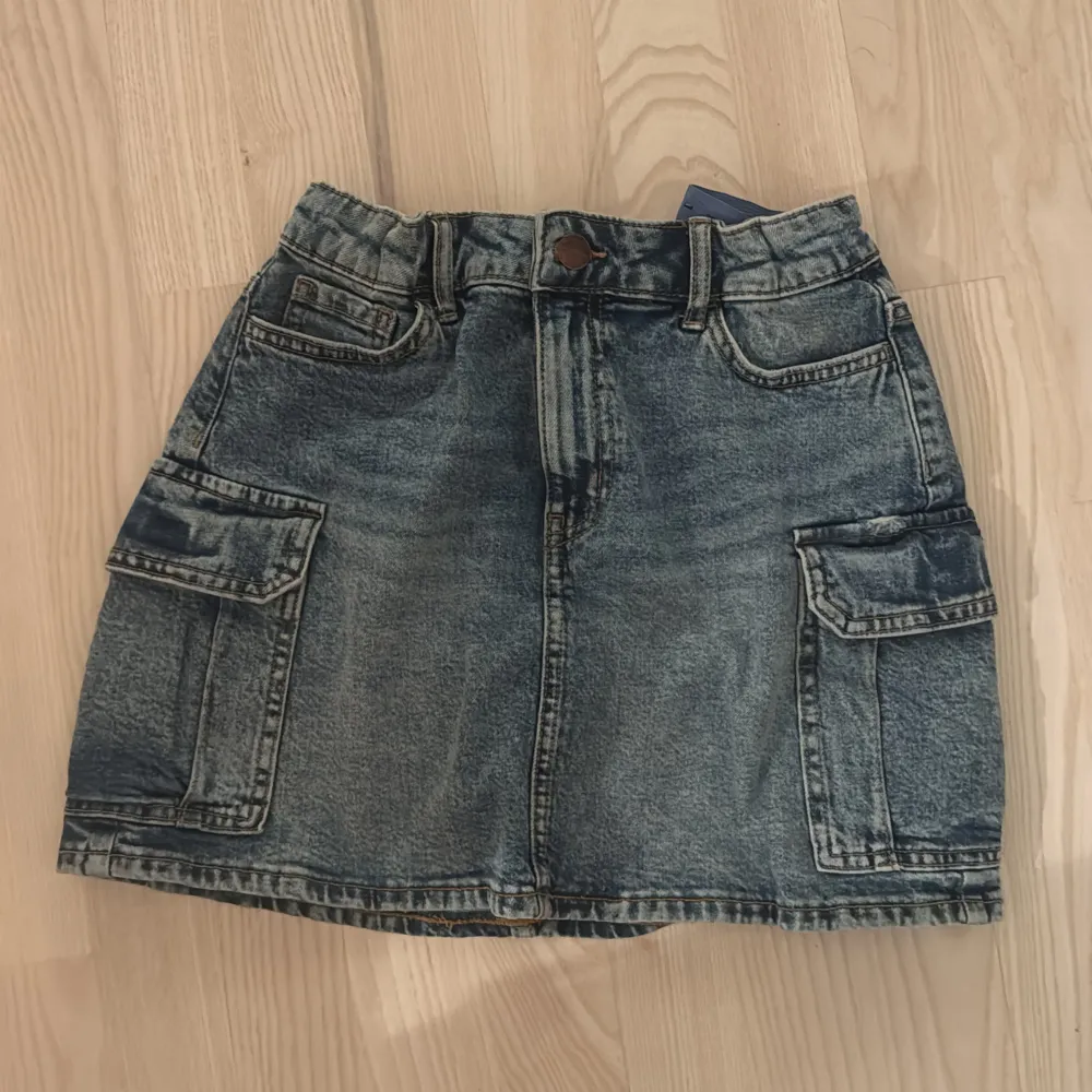 Snygg jeanskjol från Lindex i klassisk blå denim. Kjolen har praktiska fickor på sidorna och en bekväm passform. Perfekt för en avslappnad stil.. Hameet.