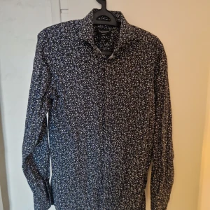 Blommig skjorta från Bruun & Stengade - Snygg blommig skjorta från Bruun & Stengade i modern passform. Skjortan har ett stilrent mönster i blått och vitt med långa ärmar. Perfekt för en trendig look!