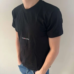 Svart t-shirt från Saint Laurent -  Säljer min snygga t-shirt från Saint Laurent då den börjar bli lite liten. Den är perfekt att ha under sommaren då den är väldigt stilren och i fin kvalité. Hör av dig ifall du har någon fråga.