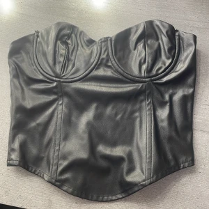Svart korsett från Zara - Snygg svart korsett från Zara i skinnimitation. Den har en dragkedja på sidan och formade kupor för en stilren look. Perfekt för en kväll ute🩷