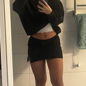 Kort kjol - En kort svart kjol med en liten slits på sidan, materialet är mjukt och töjbart