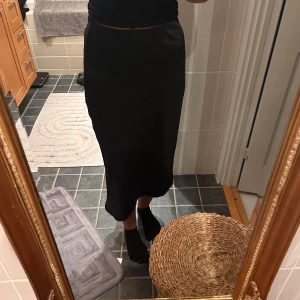 Svart asymmetrisk kjol - Svart satin kjol från Hm som är snedskuren. Storlek 36💕